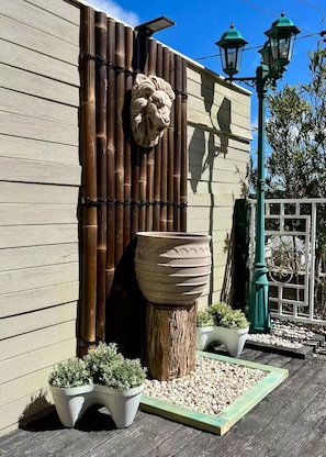 A building facade with a bamboo wall, a large planter, and two potted plants. - Cozy Mountain Cottage (Katoomba)