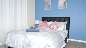 A bedroom with a bed, a nightstand, and two wall art pieces. - Cozy Mountain Cottage (Katoomba)