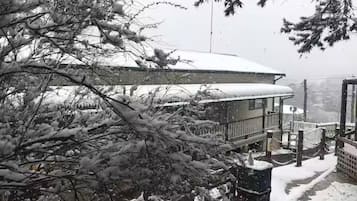 A snow-covered building with a balcony and a view of a bridge.