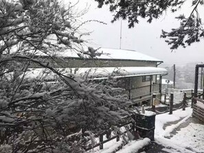 A snow-covered building with a balcony and a view of a bridge. - Cozy Mountain Cottage (Katoomba)