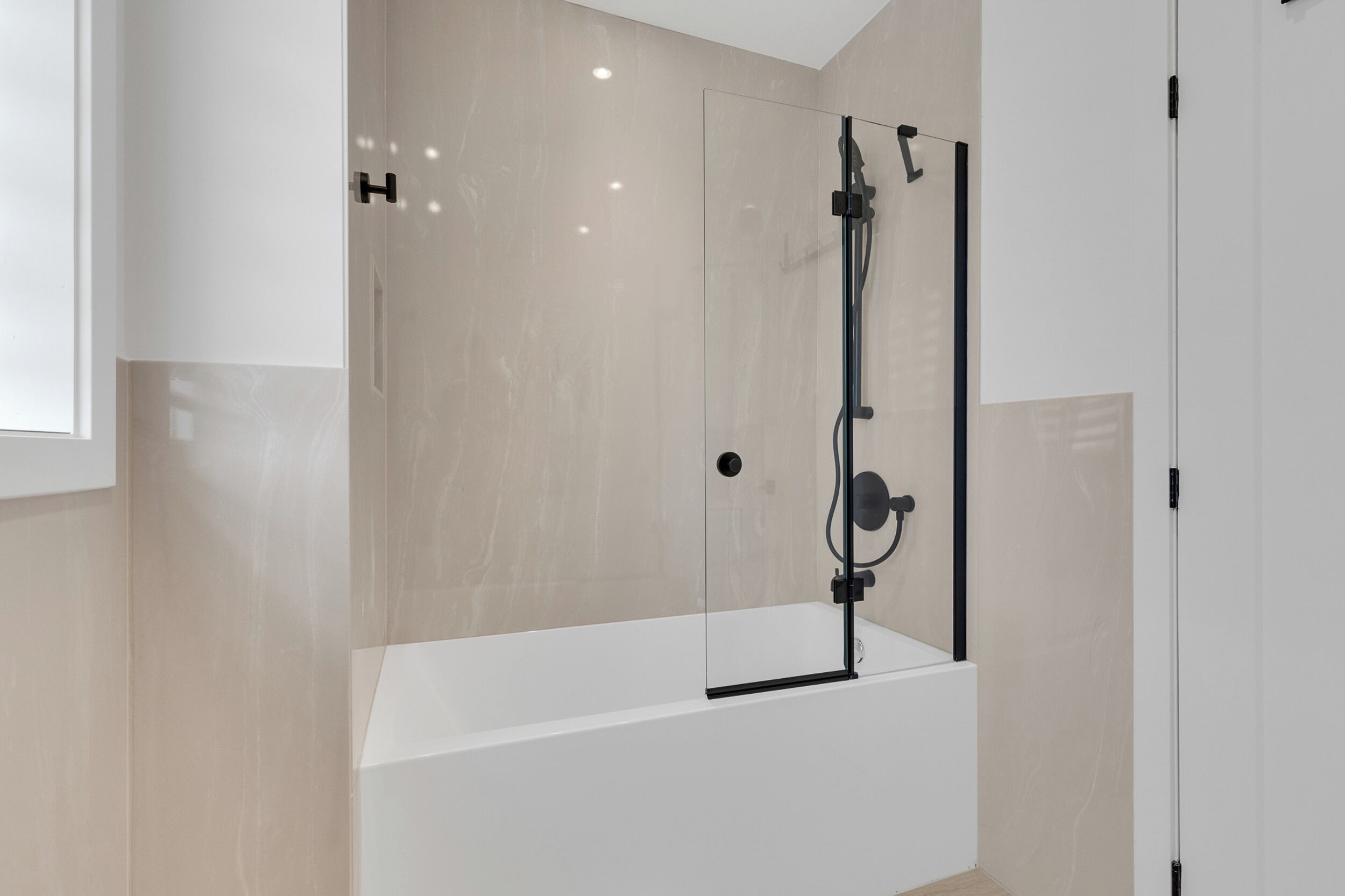 A modern bathroom with a glass-enclosed shower, a white bathtub, and a minimalist design.