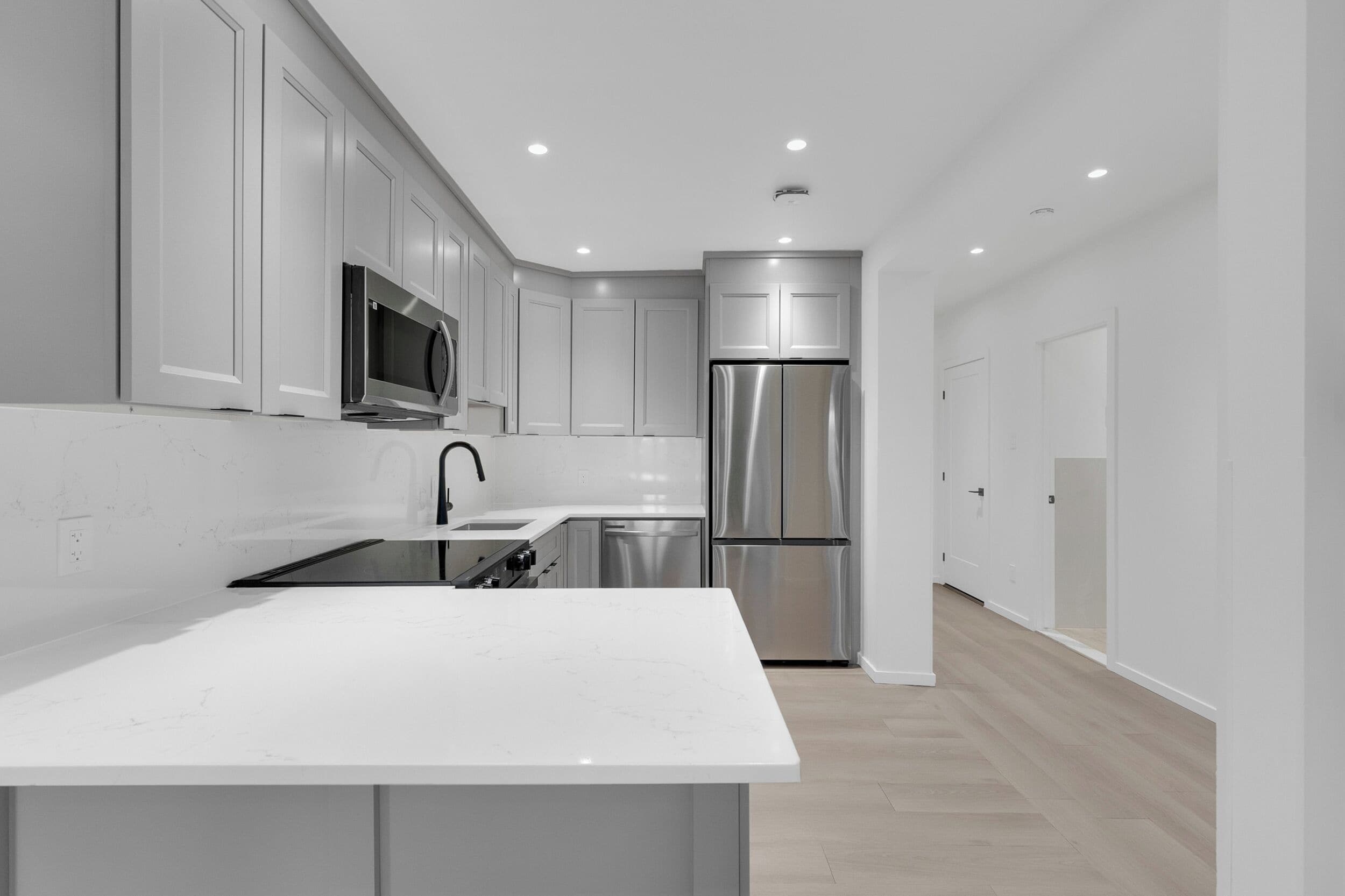 A modern kitchen with white cabinetry, stainless steel appliances, and a marble countertop.