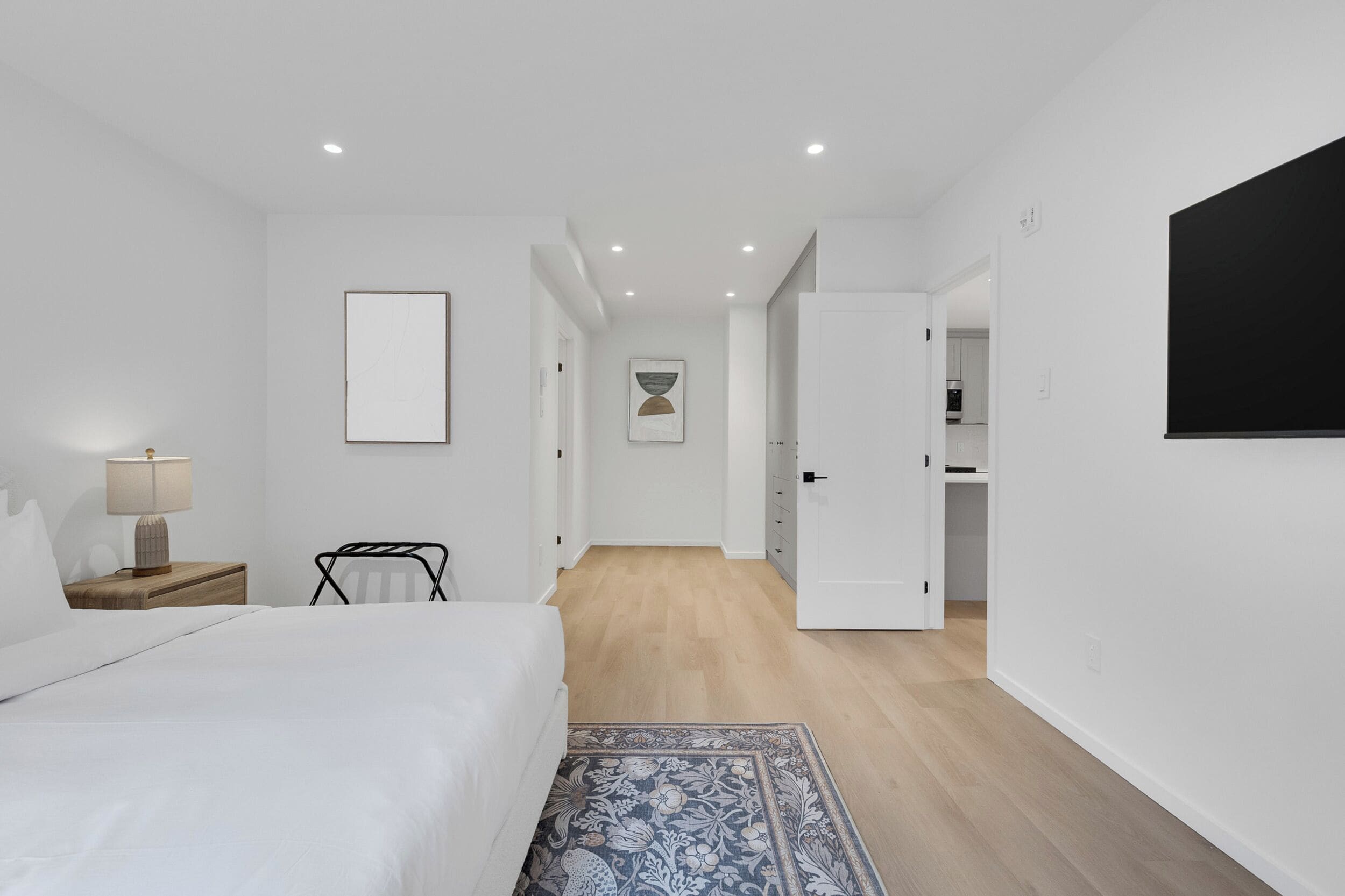 A modern bedroom with a bed, bedside table, lamp, and a blue patterned rug.