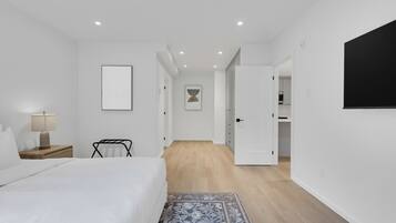 A modern bedroom with a bed, bedside table, lamp, and a blue patterned rug.