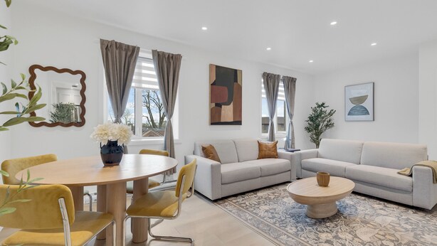 A modern living room with a sofa, coffee table, and dining area. - Le Victoria MidTown Montreal (Montréal)