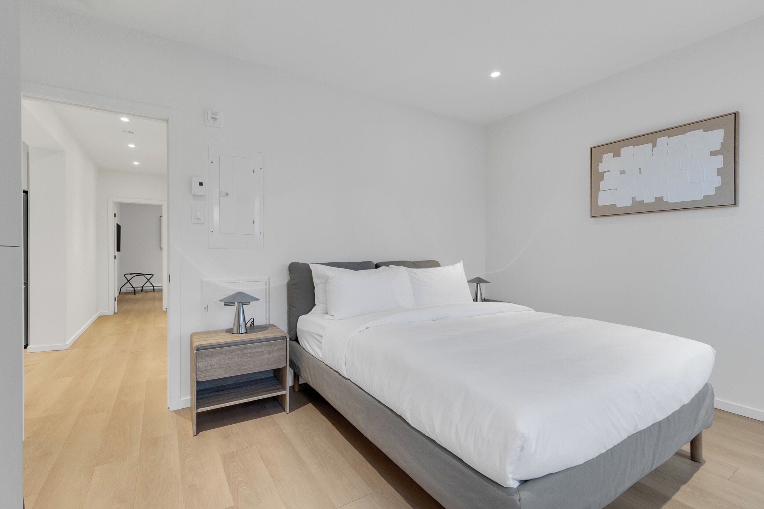Une chambre moderne avec un lit, des tables de chevet et une œuvre d’art accrochée au mur.