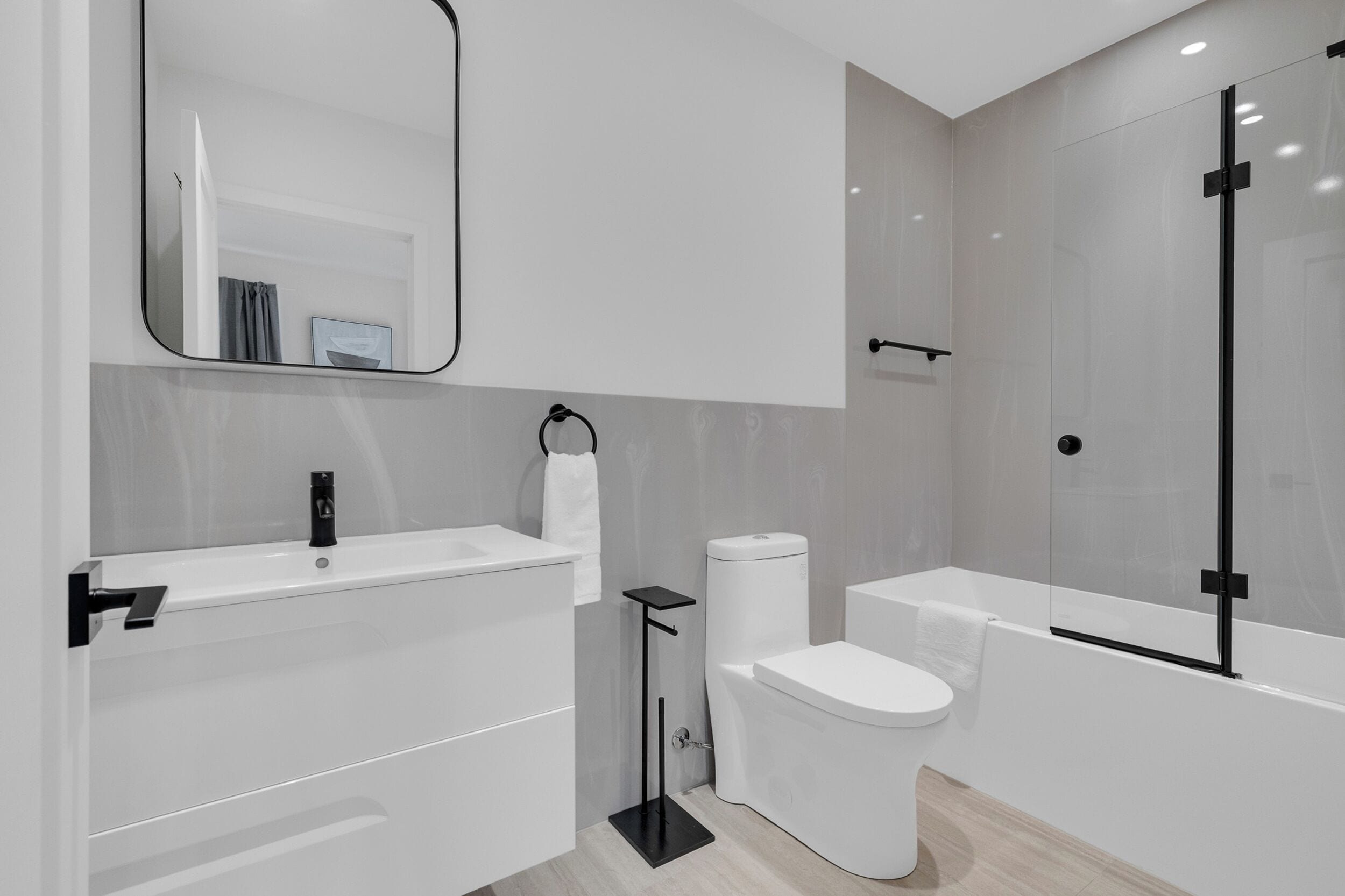 A modern bathroom with a white sink, toilet, and bathtub.