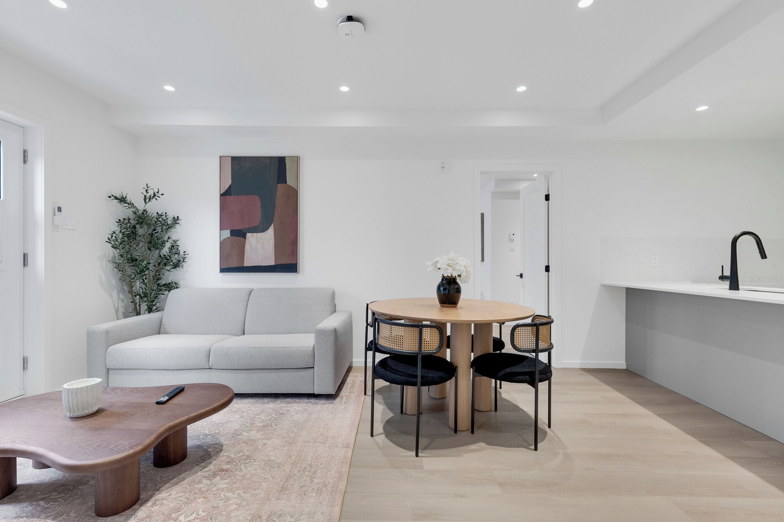 A modern living room with a sofa, a coffee table, and a dining table with chairs.