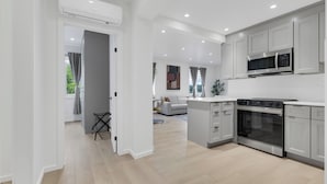 A modern kitchen with white cabinetry, a built-in oven, and a microwave. - Le Victoria MidTown Montreal (Montréal)