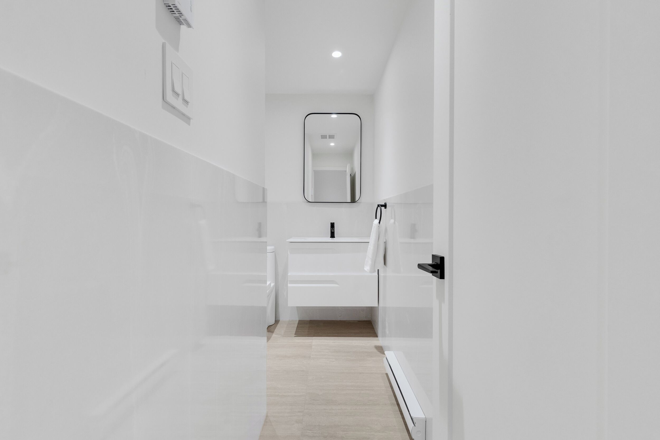 A modern bathroom with a white sink, mirror, and towel rack.