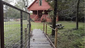 Une maison en bois rouge, dotée d’un porche et d’un escalier menant à une entrée fermée par un portail.