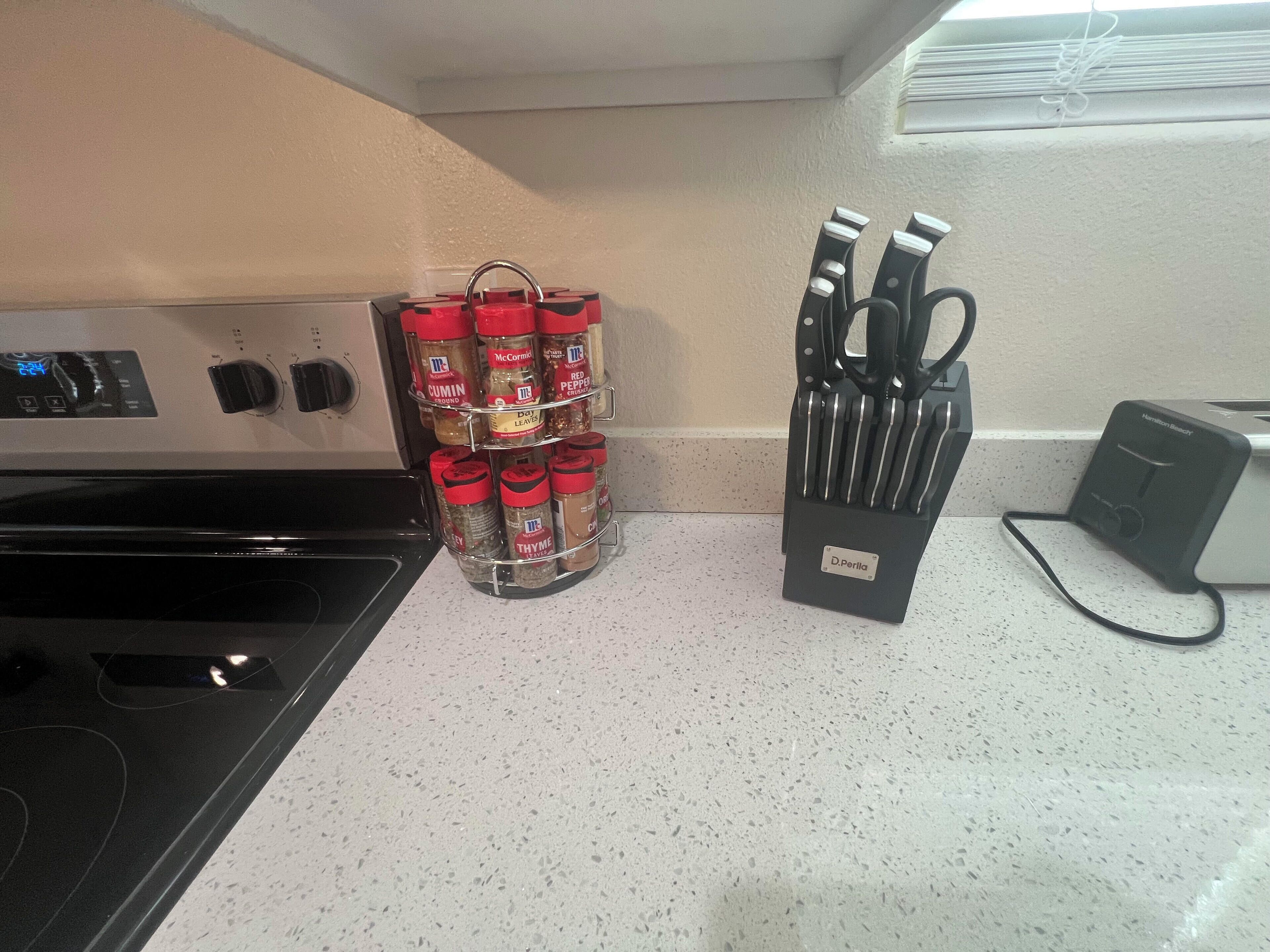 Un plan de travail de cuisine avec un étagère à épices, un bloc à couteaux et une cuisinière.