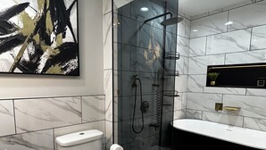 Uma casa de banho moderna com cabine de duche em vidro, sanita branca e toucador preto.