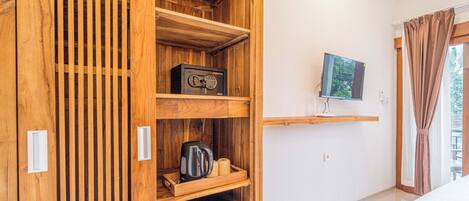 Een hotelkamer met een houten garderobe, een televisie aan de muur en een bed met een witte dekbedovertrek.