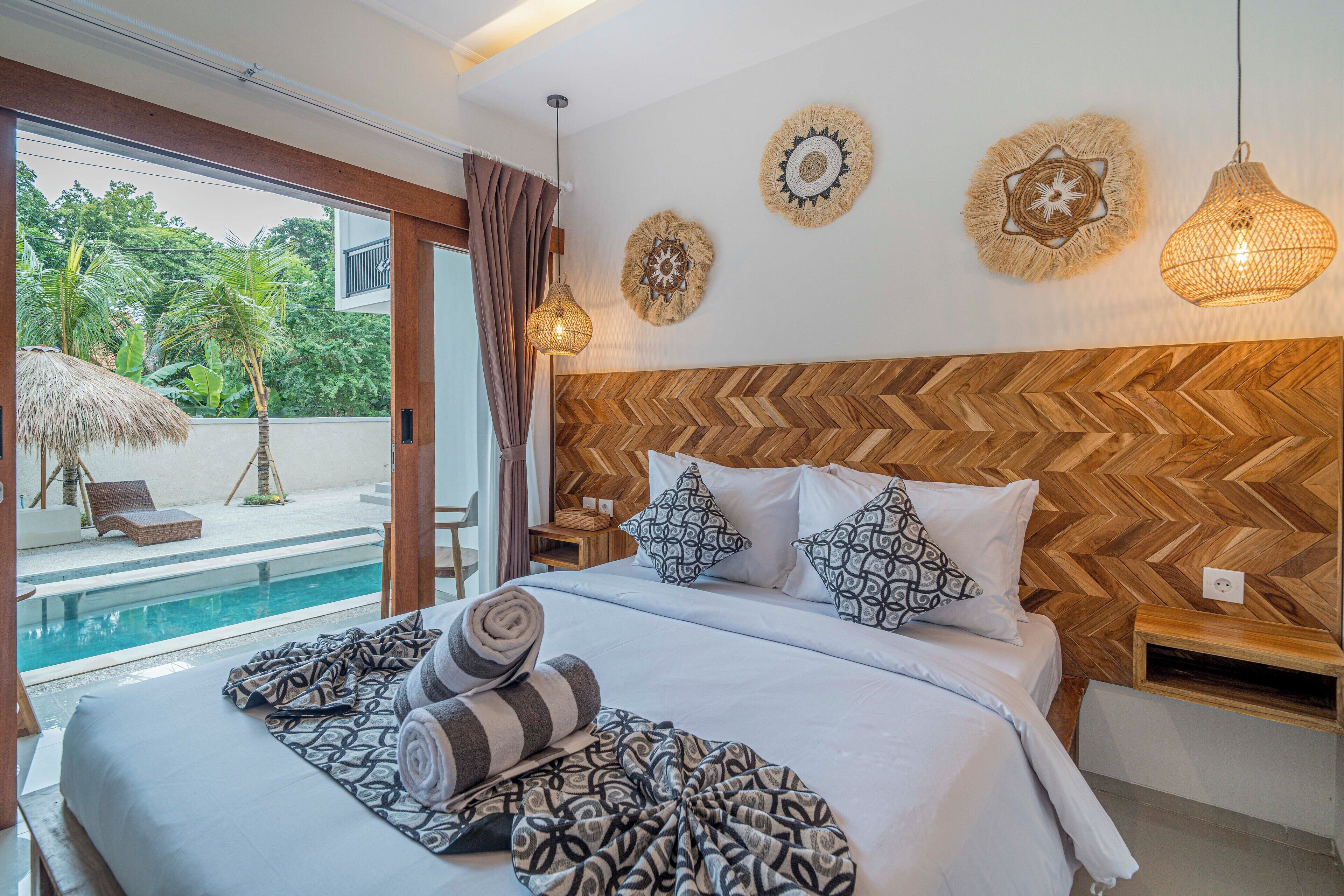 Habitación de hotel con una cama grande, un cabecero de madera en diseño espiga y vistas a la piscina, además de decoración en la pared.