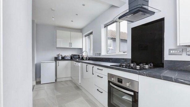 A modern kitchen with white cabinetry, a black stove, and a built-in oven. - 3 Bedroom House- Loughborough-Sleeps 5-FreeParking (Loughborough)