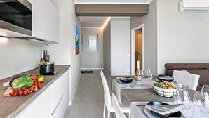 Una cocina moderna con horno integrado, un comedor con mesa para dos y una sala de estar con sofá.
