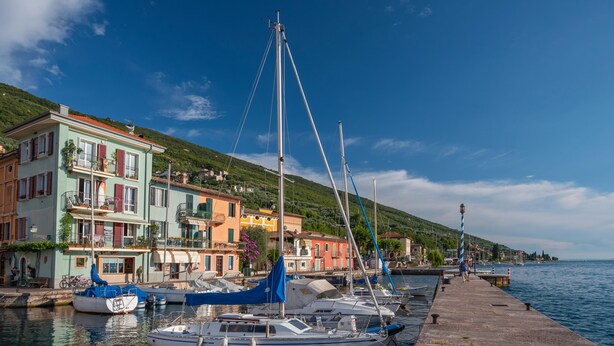 Un puerto con barcos amarrados, edificios coloridos y un cielo azul despejado.