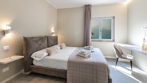 Un dormitorio moderno con cama, mesitas de noche, escritorio y una silla.
