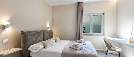 A modern bedroom with a bed, bedside tables, a desk, and a chair.