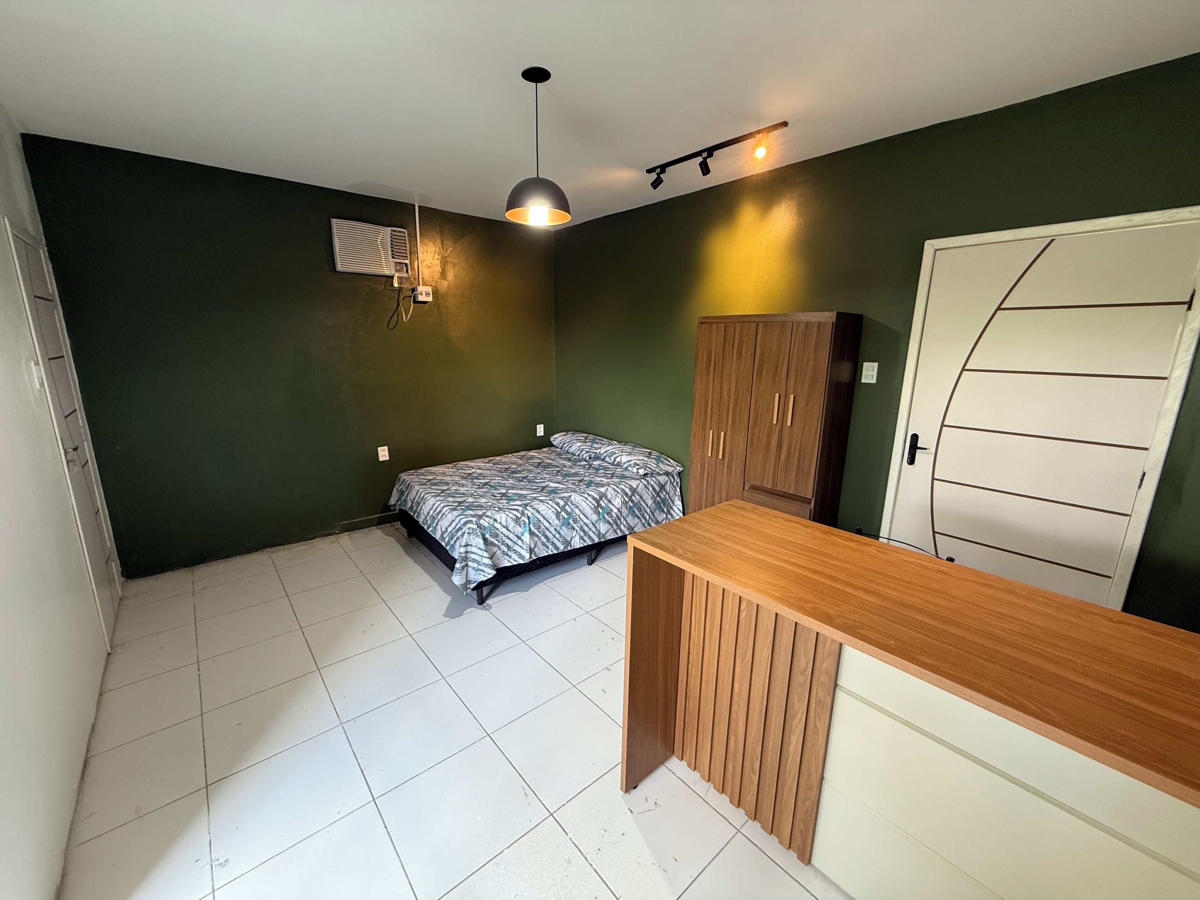 Una camera da letto con un letto, una scrivania in legno, un armadio e una porta.