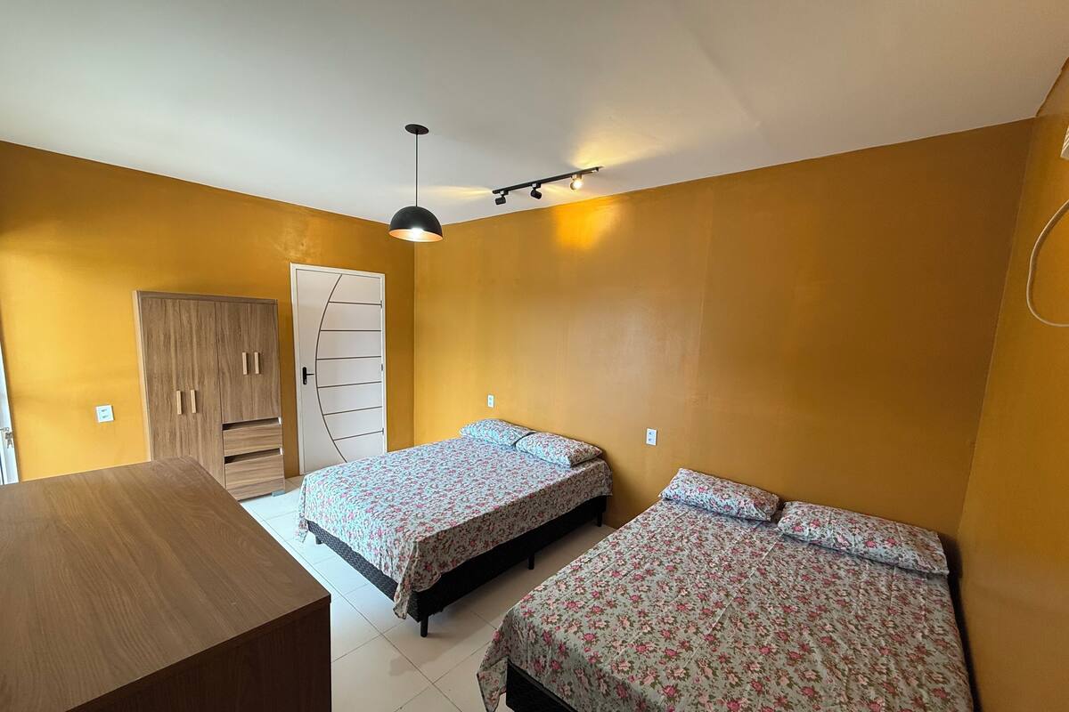 Habitación con dos camas, un armario de madera y una lámpara en el techo.