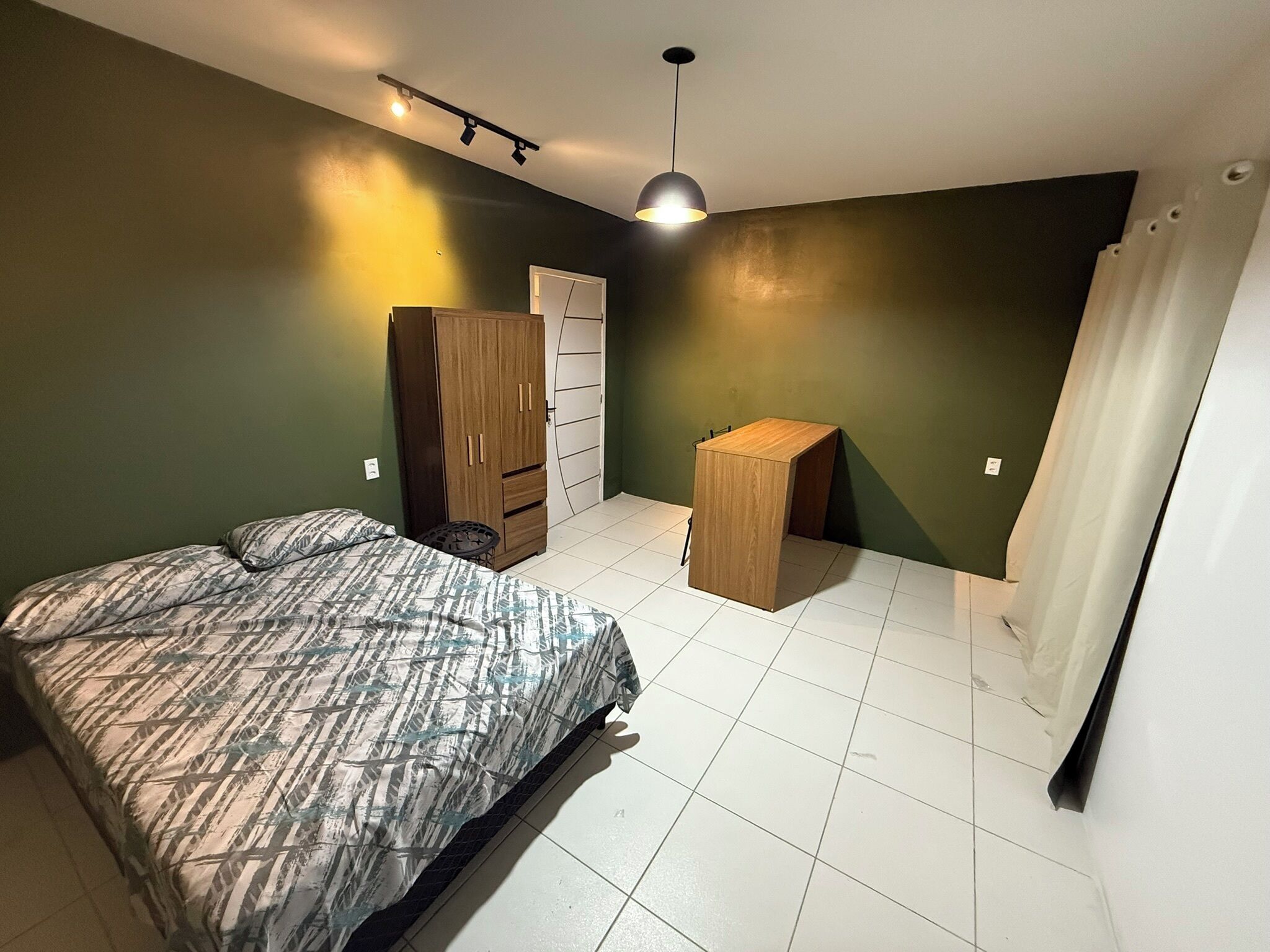 Ein Schlafzimmer mit einem Bett, einem Kleiderschrank, einem kleinen Holztisch und einem Vorhang.