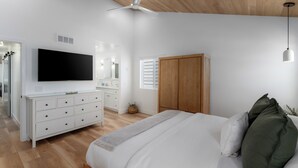 A bedroom with a bed, a TV, a wardrobe, and a ceiling fan.