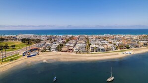 An aerial view of a coastal town with a beach, boats, and a roller coaster.