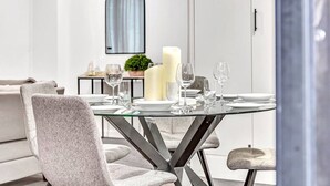 A modern dining area with a glass table set for four, surrounded by grey upholstered chairs. - Stellar Apartments 3 bedroom apartment with rooftopviews overlooking the city (Kent Town)