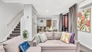 A modern living room with a sofa, a coffee table, and a staircase. - Stellar Apartments 3 bedroom apartment with rooftopviews overlooking the city (Kent Town)