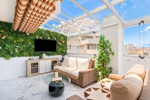 Un salon moderne doté d’un plafond en verre, d’un téléviseur à écran plat, d’un canapé, d’une table basse et d’une plante.
