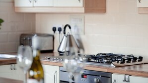 A kitchen with white cabinets, a stainless steel range hood, a gas stove, and a digital oven control. - Lodge 2 by Interhome (Boat of Garten)