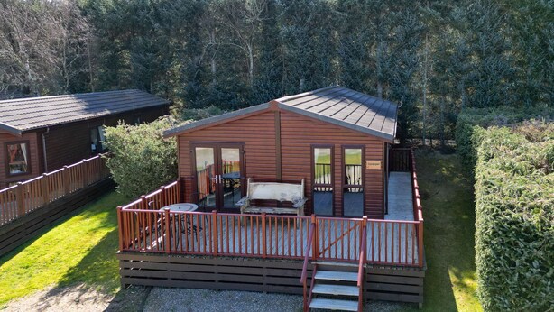 A wooden cabin with a deck and a small staircase leading to the entrance. - Lodge 2 by Interhome (Boat of Garten)