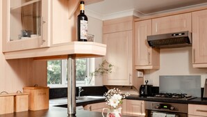 A modern kitchen with wooden cabinets, a black countertop, a stainless steel sink, and a decorative pitcher with flowers. - Lodge 7 by Interhome (Boat of Garten)