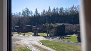 A view of a campground with several cabins, a dirt road, and surrounding trees. - Lodge 5 by Interhome (Boat of Garten)