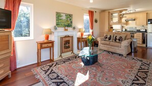 A living room with a fireplace, a sofa, a coffee table, and a television. - Lodge 5 by Interhome (Boat of Garten)