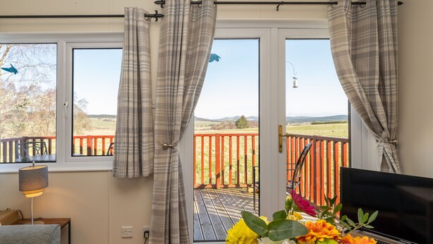 A room with a TV, a desk, and a window with curtains. - Lodge 3 by Interhome (Boat of Garten)