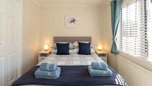A neatly made bed with two pillows, a bedside lamp, and a framed picture on the wall. - Lodge 3 by Interhome (Boat of Garten)