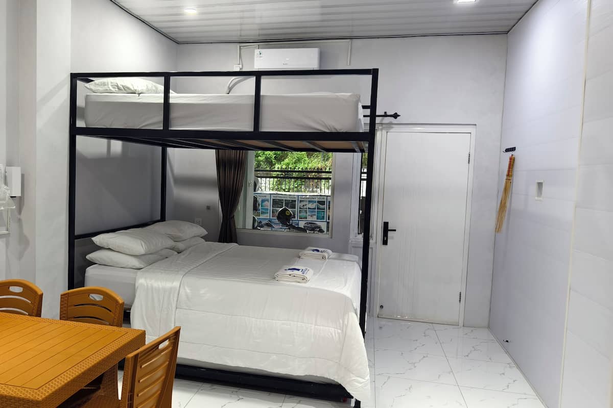 Een slaapkamer met stapelbed, een tafel en stoelen, een raam met uitzicht en een deur.
