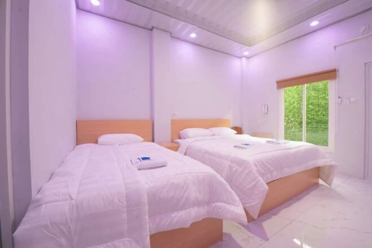 Een kamer met twee bedden, een raam en een deur.