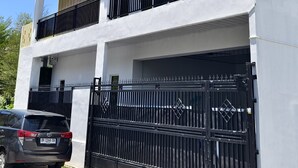 A modern two-story building with a garage, black metal railings, and a clear glass roof. - Lombokhouse Mandalika (Kuta)