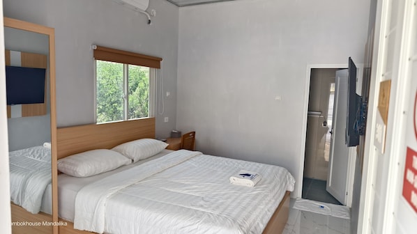 Quarto com cama grande, janela com vista para árvores, cabeceira de madeira, mesa de cabeceira e espelho.