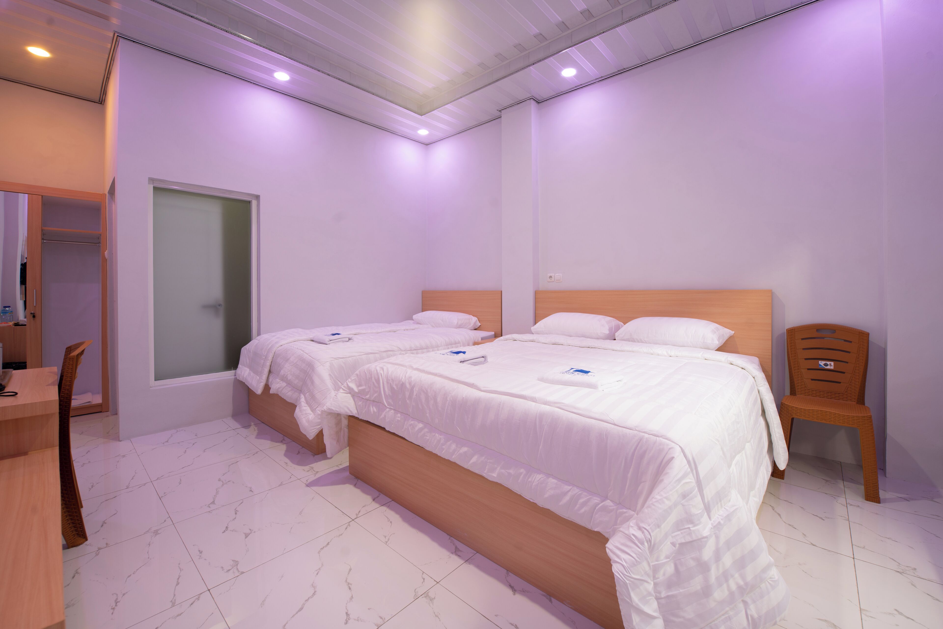 Una habitación de hotel moderna con dos camas, un escritorio de madera y una silla.
