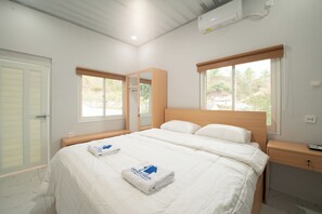 Quarto com uma cama grande, duas janelas, cabeceira de madeira, mesa de cabeceira e um espelho.