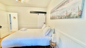 Ein Schlafzimmer mit einem Bett, einem Bild, einer Lampe und einer Tür.
