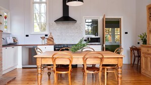 Una cocina con una mesa y sillas de madera, estufa y pileta.