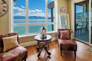 Enjoy a serene lake view from the comfort of your room, featuring a large window, plush armchairs, and a cozy seating area.