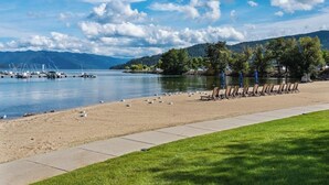 Une plage au bord d’un lac, avec une rangée de chaises et une promenade en béton.