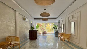 Passadís amb sòl motllurat, mobles de vimet i una planta al centre.